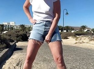 girl pisses in jeans shorts at the street in public